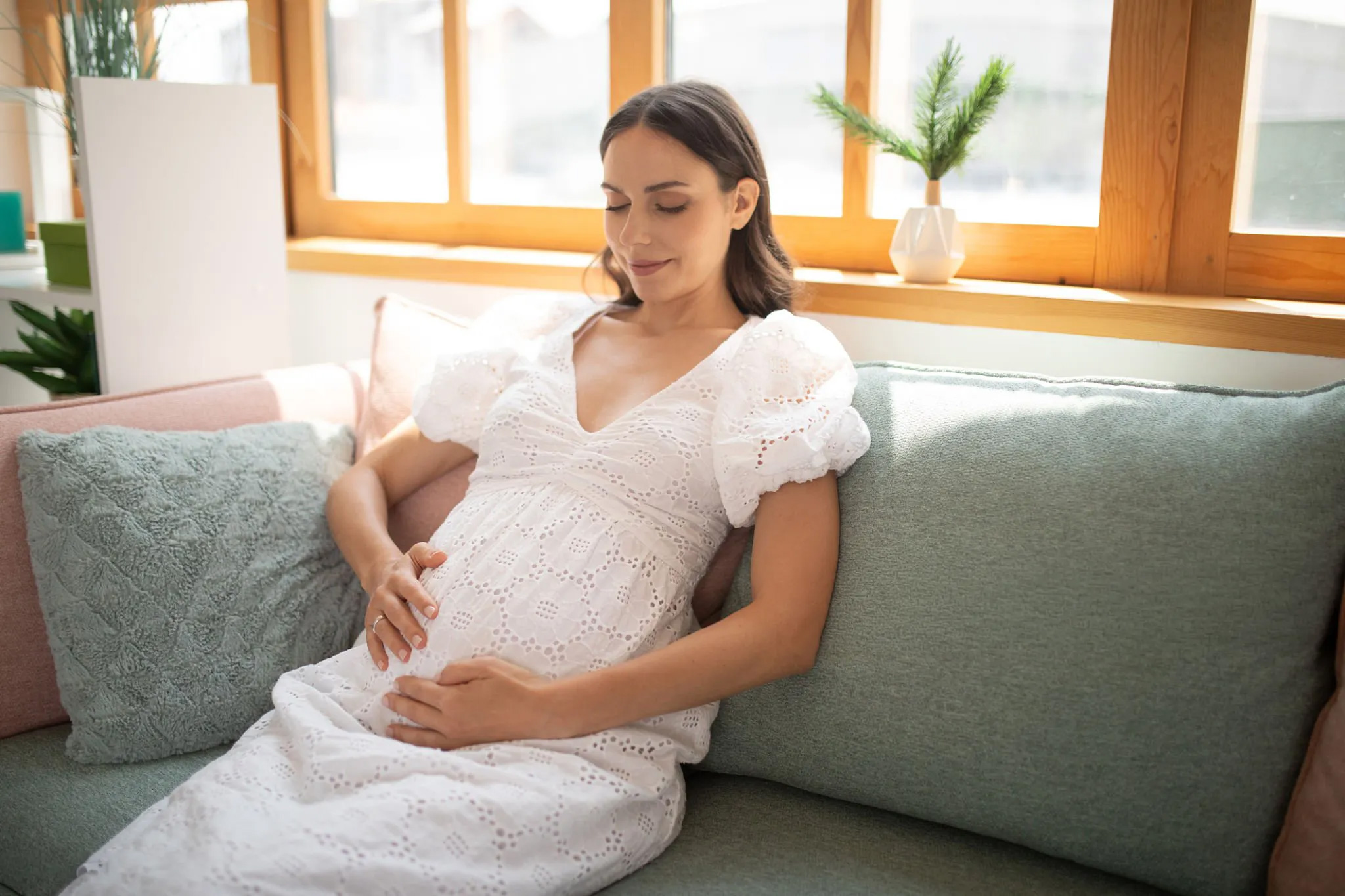 Femme enceinte tenant son ventre dans une ambiance calme pour représenter l’accompagnement périnatal