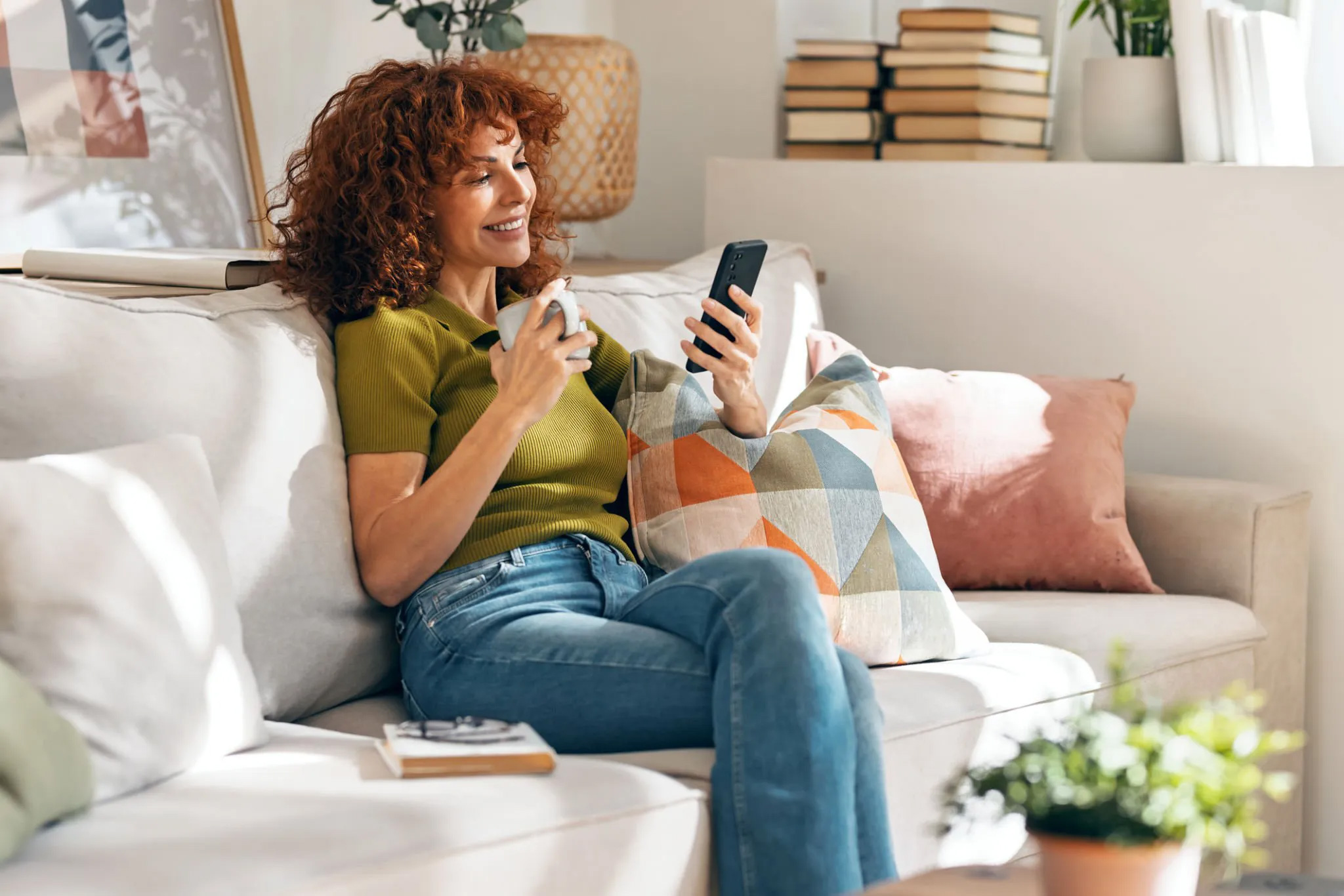 Femme consultant son téléphone dans une ambiance chaleureuse pour représenter le contact avec Hypnose Double Maman